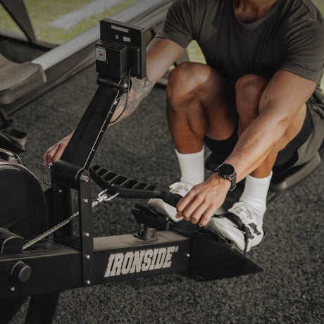 Athlete strapping into an IRONSIDE air rowing machine for HYROX and hybrid fitness training - HYROX gym equipment Canada