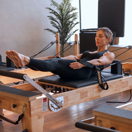 Woman training on an IRONSIDE Pilates reformer machine in a studio - commercial and home Pilates equipment Canada