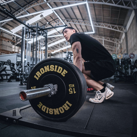 Lifter loading IRONSIDE bumper plates on an Olympic barbell for deadlift - powerlifting equipment Canada
